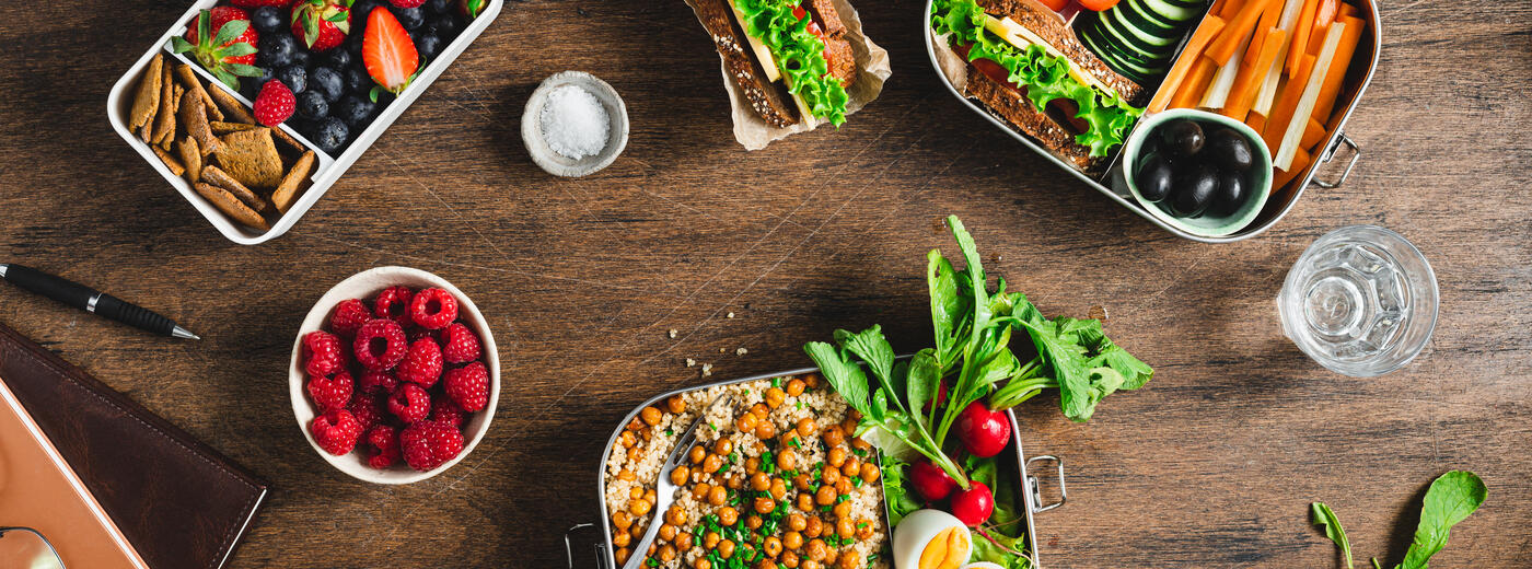 Meal prep containers with various food items on a wooden table top